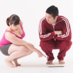 体重計に乗る男性と見ている女性