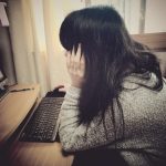 背中を丸めながらパソコンする女性